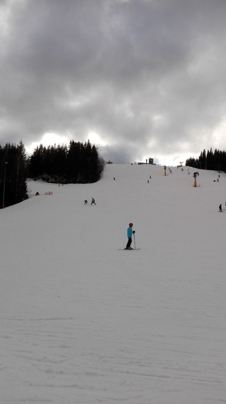 A skier enjoying the slopes at Isaberg Mountain Resort in Hestra, South Sweden. The snowy winter sports scene includes a ski lift and a chalet in the background.