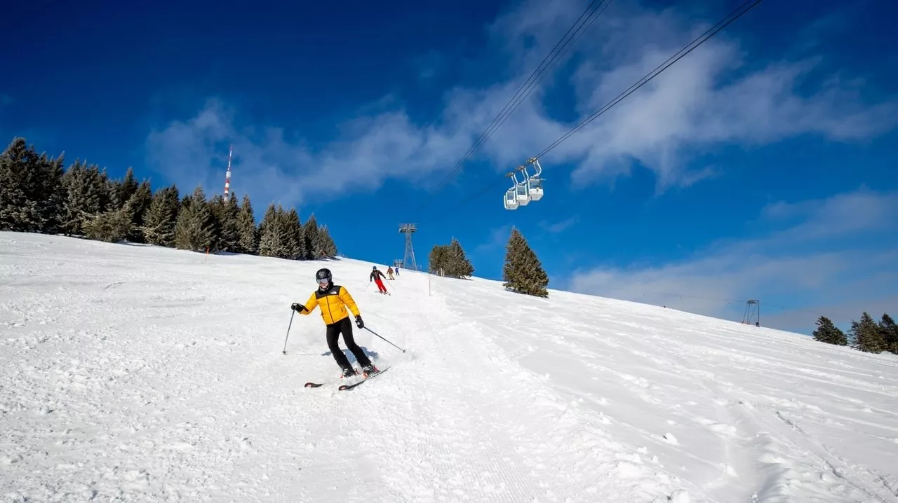 Skiers and snowboarders enjoy the slopes at Beatenberg-Niederhorn ski resort in Switzerland traversing the snowy landscape and using the ski lift.