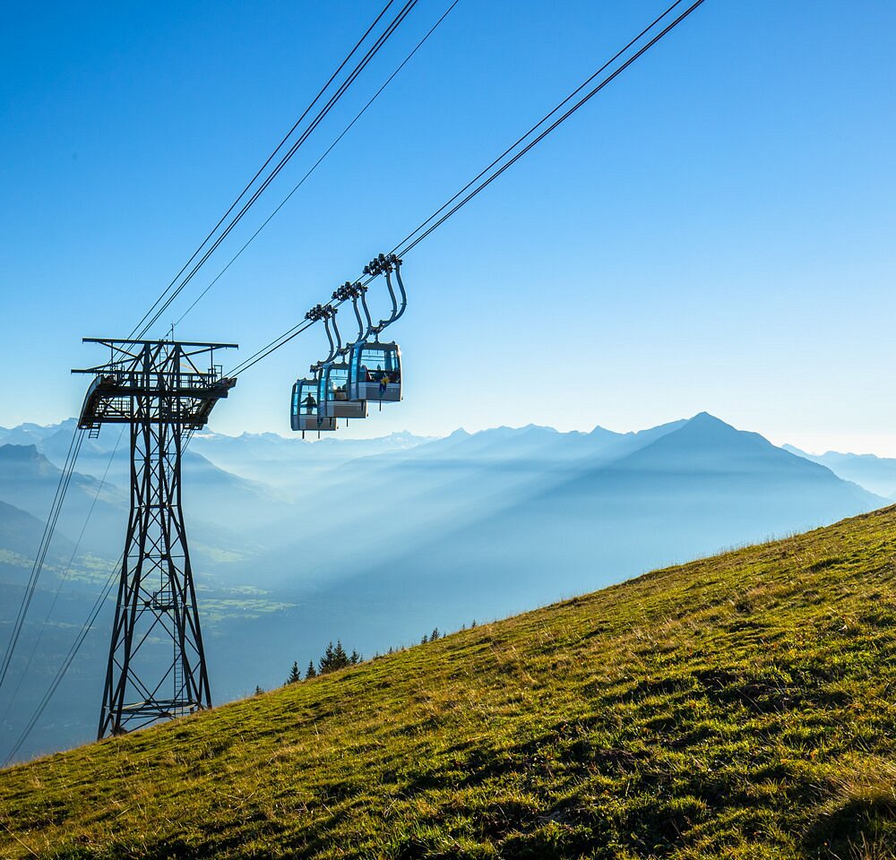 Breathtaking view of Beatenberg-Niederhorn ski resort in Switzerland featuring a ski lift serving the mountainous terrain, a charming chalet nestled into the snowy landscape, and a winter sports scene underway.