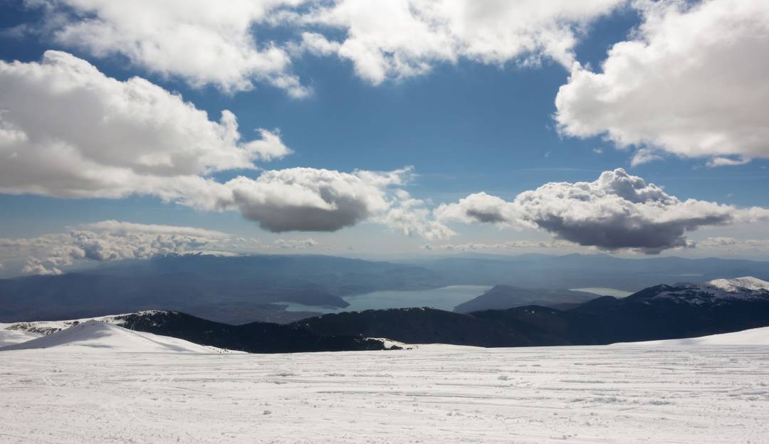 A picturesque winter scene in Voras – Kaimaktsalan, Edessa, Greece, featuring a ski sports setting, a beautiful chalet amidst snow-laden trees, and a majestic mountain in the backdrop.