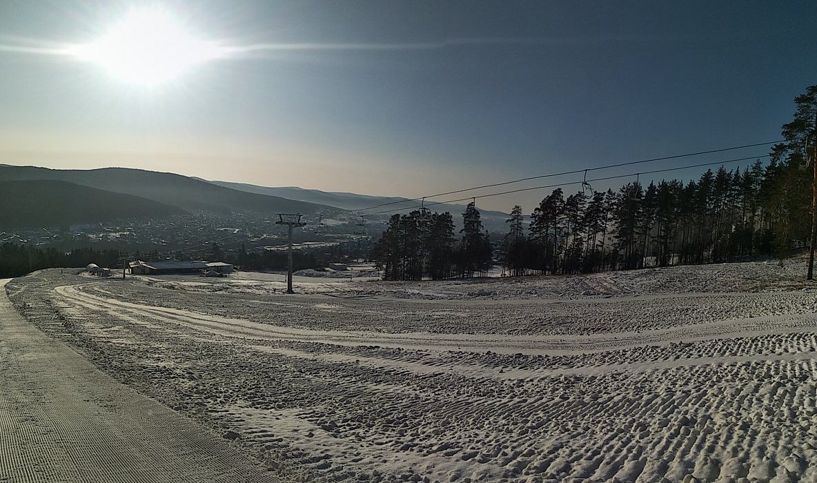 View of Mratkino ski resort in Beloretsk, Russia, displaying stunning winter scenery complete with snow covered slopes, a charming chalet, and vibrant winter sports activity.