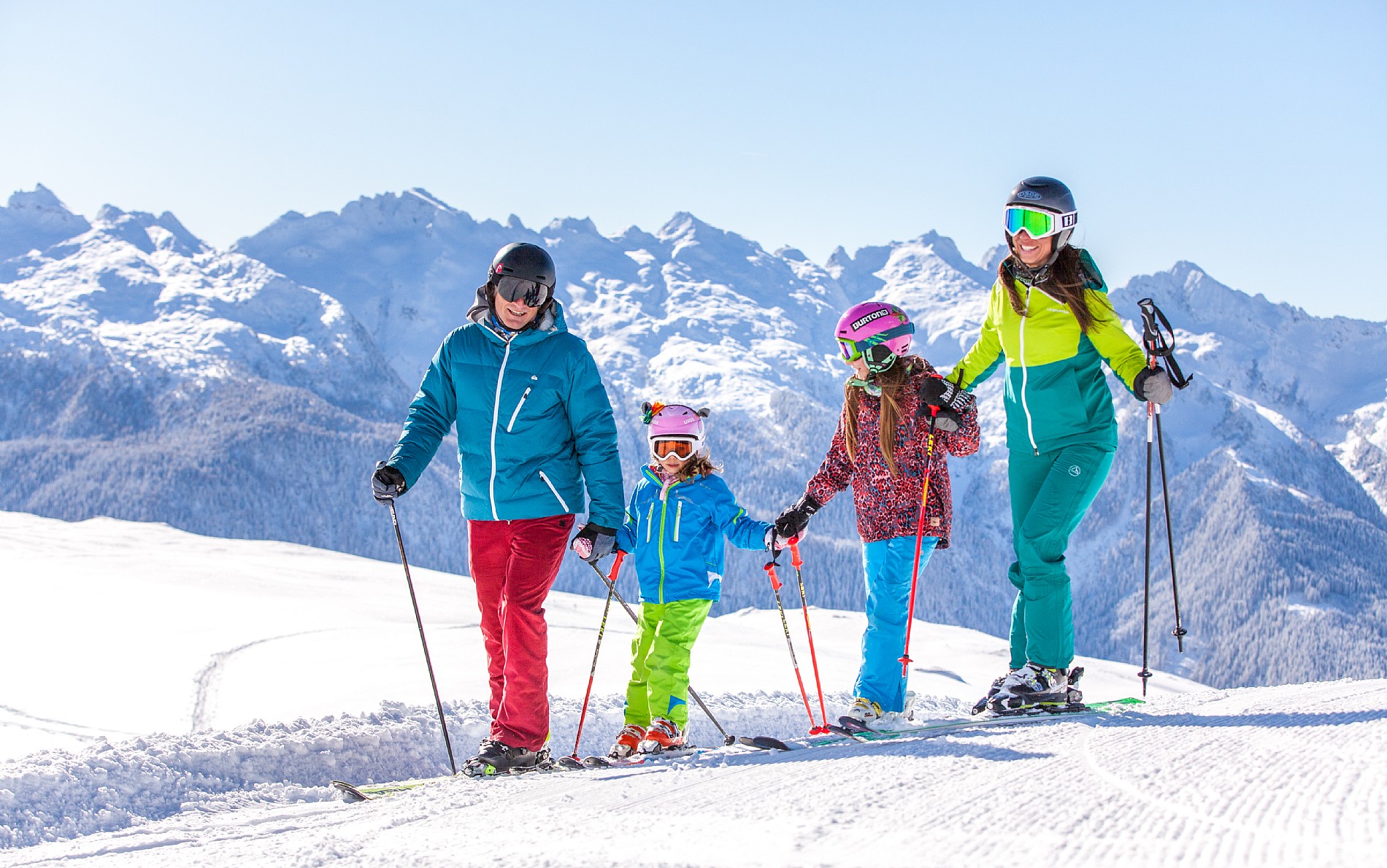 A family and group of skiers enjoying a day on the snowy slopes at the picturesque Alpe Lusia ski resort in Trentino Italy with a charming chalet in the background.