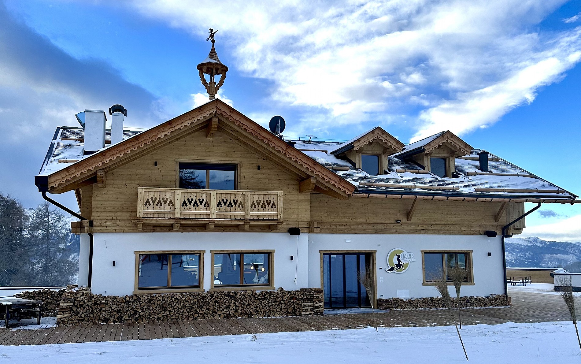 View of Alpe Lusia winter sports centre in Moena, Italy, featuring ski slopes, a cozy lodge, and a charming chalet amidst a picturesque winter landscape.