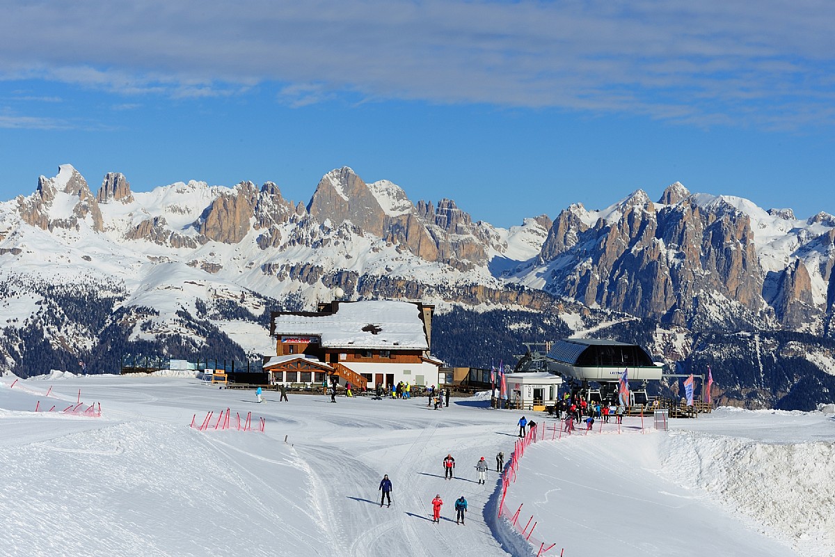 Alpe Lusia – Moena | Bellamonte in Italy - a group of people skiing down a snowy slope.