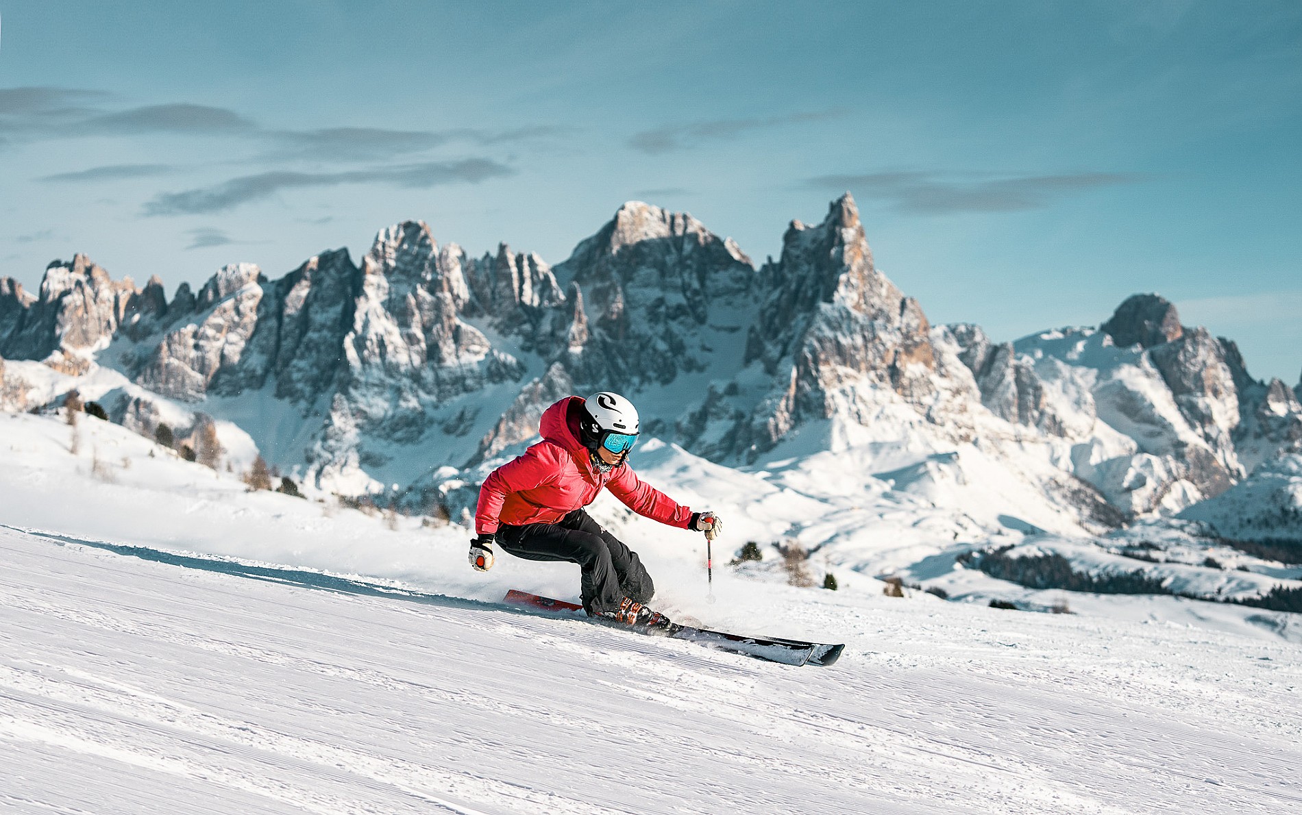 A skier and a snowboarder enjoying a winter sports scene at Alpe Lusia in Trentino, Italy. A family is having a skiing session near a quaint chalet, surrounded by snow-covered landscapes.