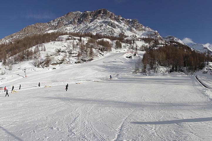 A charming ski resort scene in Valgrisenche Italy with a cozy challet nearby skiers enjoying the winter sports centre and the panoramic winter beauty.