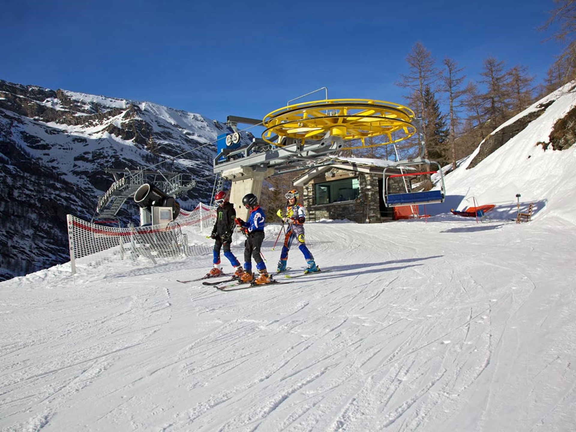 View of Valgrisenche in Italy, exhibiting a bustling winter sports centre and ski resort. You can spot a ski lift, hinting the possibility of downhill skiing and a quaint challet nestled amidst the snow.