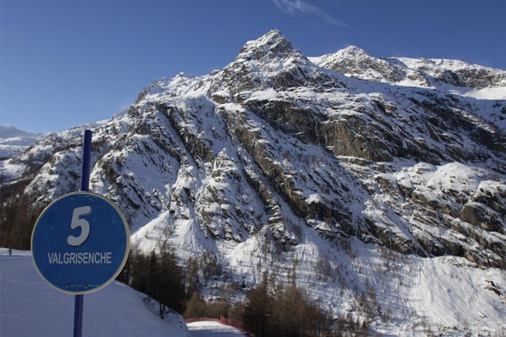A picturesque view of a chalet in Valgrisenche Italy nestled against a backdrop of snow-covered mountains. The scene is part of a ski resort presenting an inviting winter sports destination.