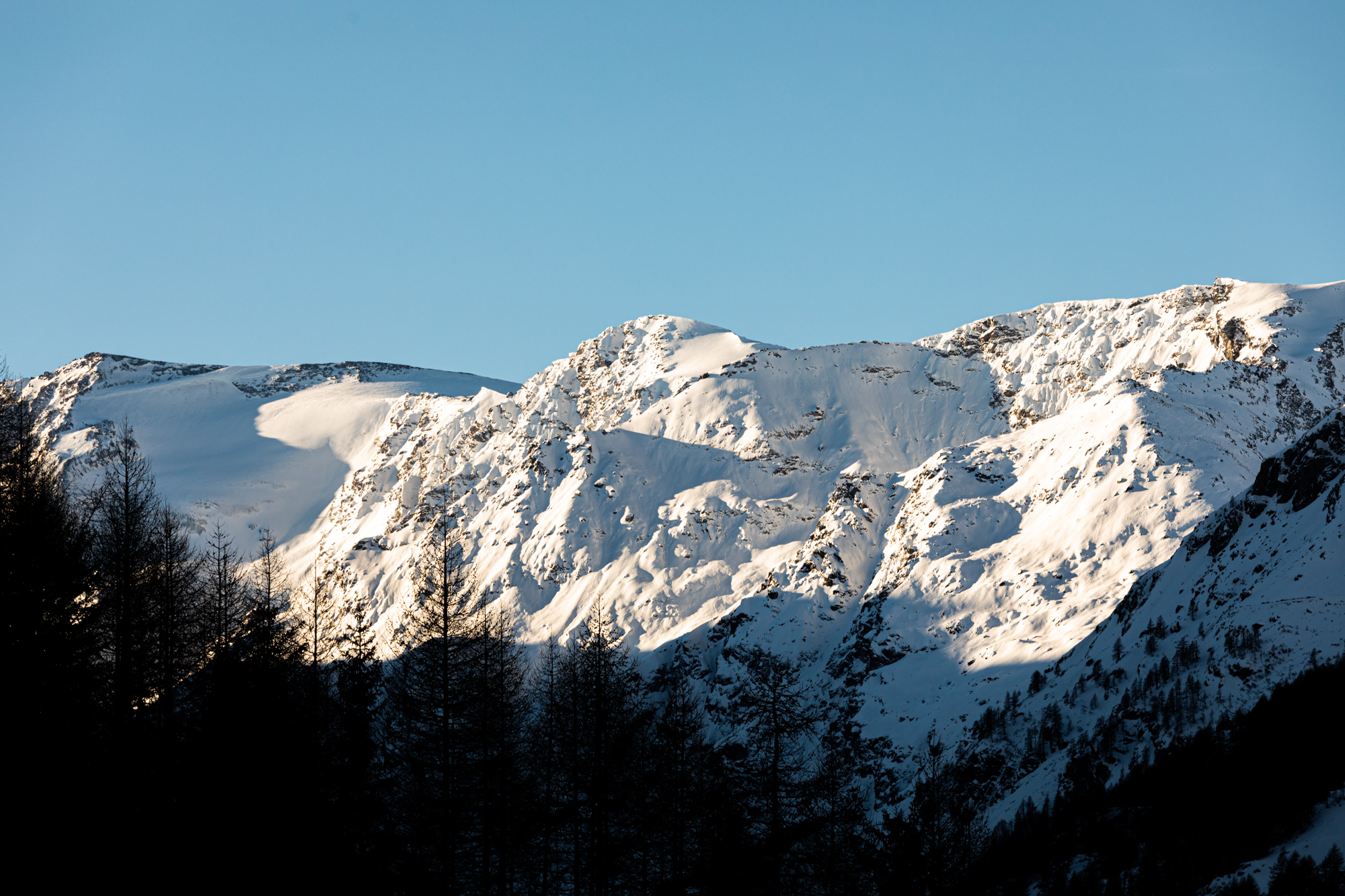 A scenic winter view in Valgrisenche Italy featuring a charming chalet amidst a snow-covered mountain landscape invoking the atmosphere of a winter sports scene.
