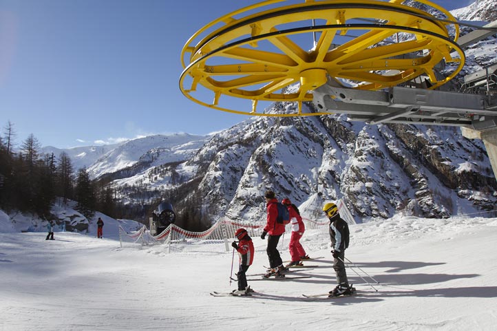 Winter sports scene at Valgrisenche in Gran Paradiso Italy featuring a ski resort with a ski lift leading up to snowy slopes with a quaint chalet in the backdrop.
