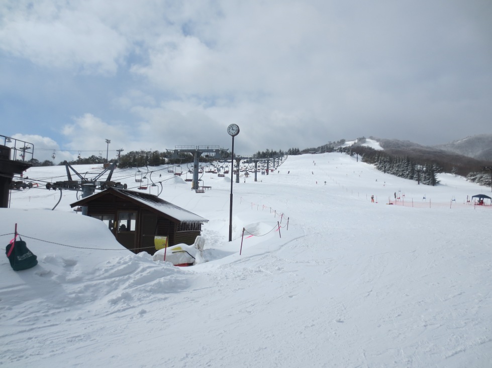 A winter scene at a ski resort in Osa, Japan, featuring a ski lift amidst the snowy landscape. Nearby, a challet beckons skiiers for warmth and rest.