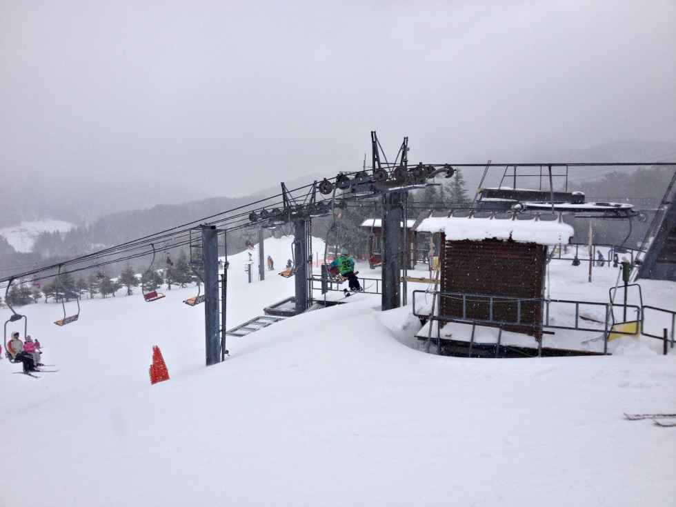 An inviting winter sports scene at a ski resort in Osa, Japan, with a ski lift trailing up to the snow-covered slopes. A picture that encapsulates the vibrancy of winter sports.