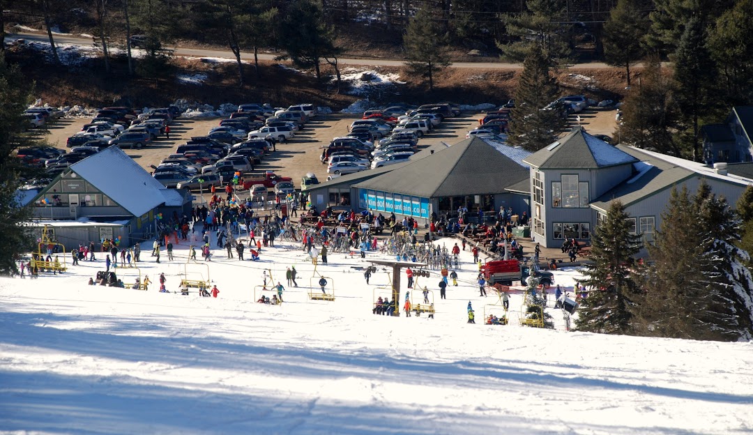 A winter sports scene at sundown in New Hartford Connecticut USA featuring a ski resort with a ski lift and people enjoying their time skiing.