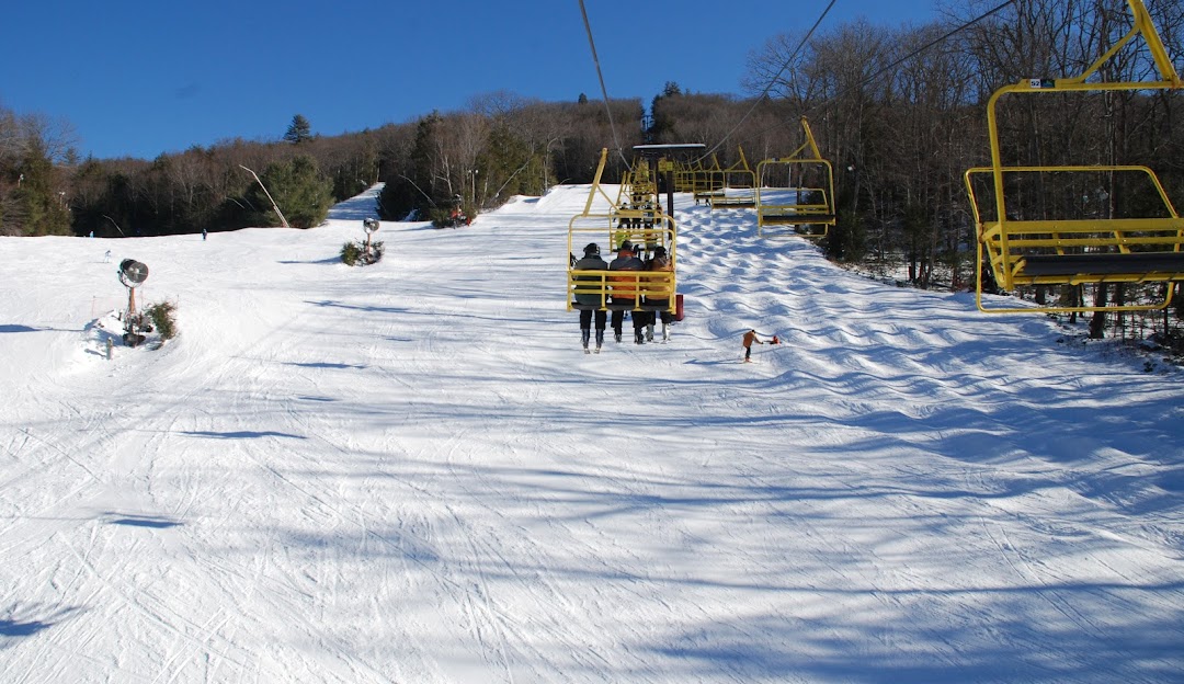Sundown at a ski resort in New Hartford, Connecticut, featuring a ski lift against the backdrop of snow-covered slopes bustling with winter sports activity.