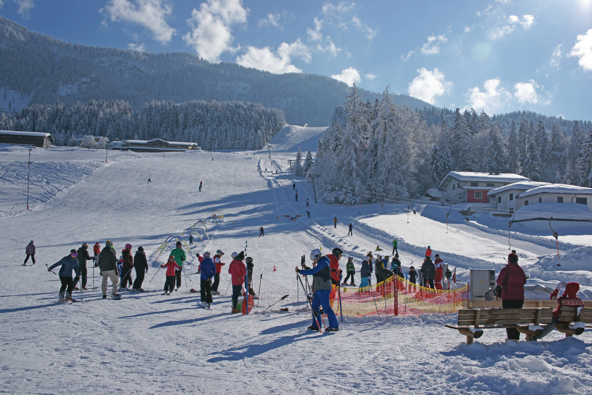 Winter sports enthusiasts enjoying a day at Schneeberglifte – Mitterland ski resort in Tyrol, Austria, flanked by chalets and ski lifts.