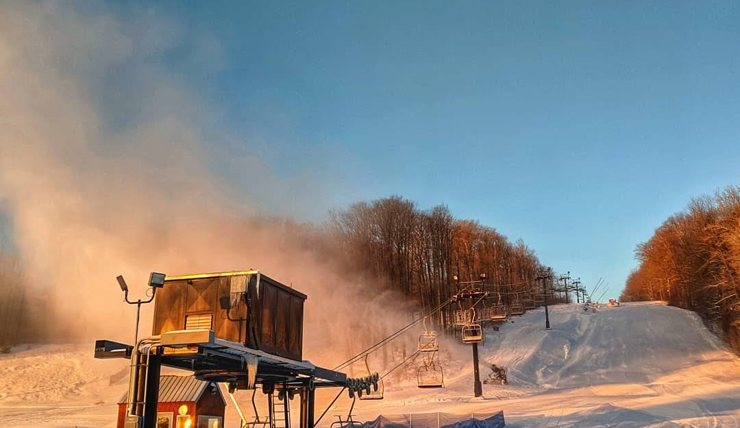 Image showcasing the picturesque winter scene at Mount Pleasant of Edinboro Ski Resort in Cambridge Springs, Pennsylvania. Features include snowy slopes, busy with winter sports, and a ski lift amidst the stunning scenery.