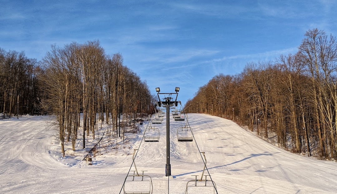 A ski lift ascends the snowy slopes of Mount Pleasant of Edinboro a ski resort in Cambridge Springs Pennsylvania with winter sports enthusiasts enjoying their activities.