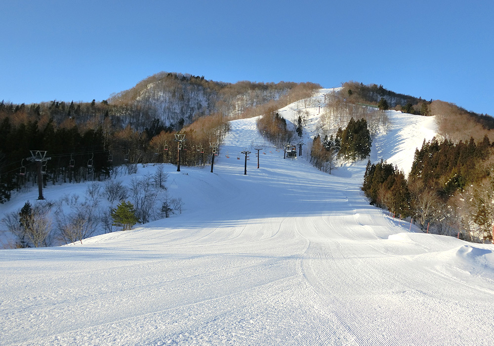 A winter sports scene at St Mary in Tōhoku Japan showcasing a ski resort with snow-covered slopes a ski lift and a chalet amidst serene surroundings.