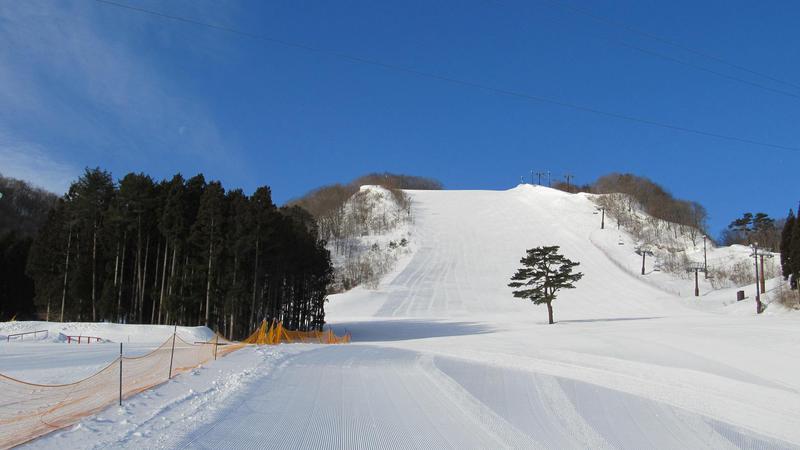 Winter sports scene at St Mary in Tōhoku, Japan, featuring a chalet and a ski resort against a stunning winter backdrop. A skier can be spotted enjoying the snowy conditions.