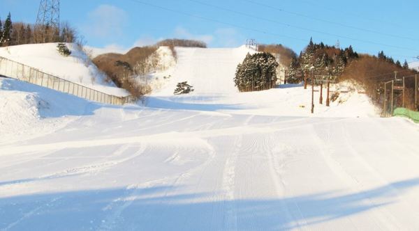 A lively winter sports scene at St Mary in Tōhuku Japan featuring a chalet backdrop with a sports center nearby. Snowmobiles add to the charm of the frosty panorama.
