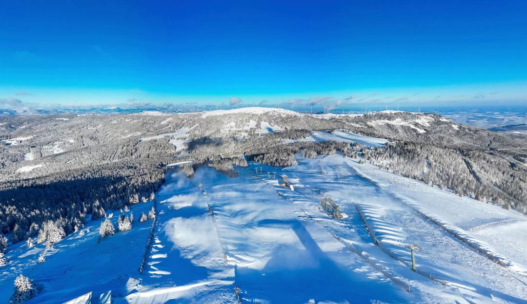View of Weinebene ski resort in Lower Carinthia Austria featuring snow-covered slopes bustling with winter sports activities amid stunning winter scenery.