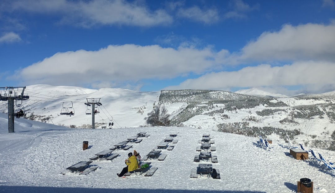 A ski resort in Leitariegos León Spain featuring a challet and a ski lift amidst a winter sports scene on snow-covered slopes.