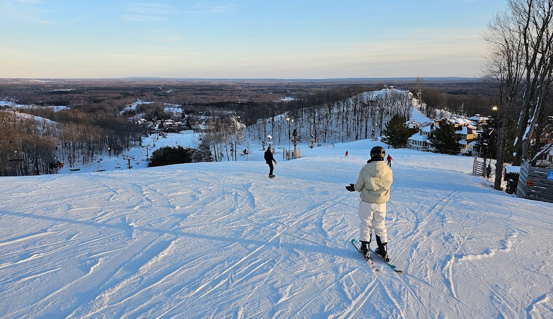 A vibrant winter sports scene at Crystal Mountain, Michigan, featuring an active skier gliding down the snowy slopes against the backdrop of the cozy ski resort and challet.