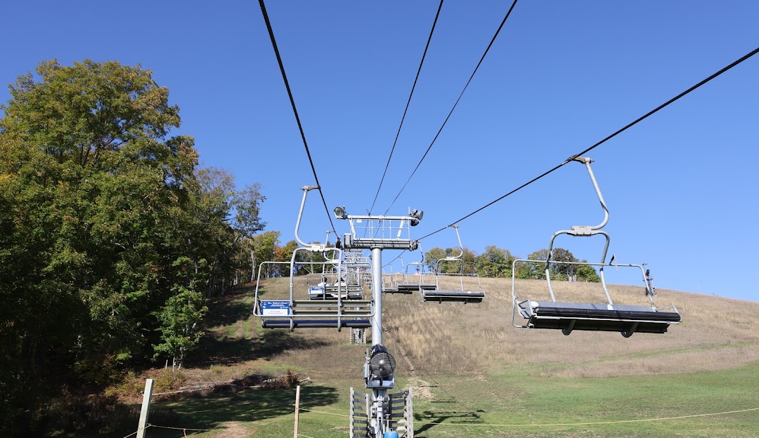 A picturesque view at Crystal Mountain Ski Resort Michigan prominently featuring a ski lift navigating a snowy slope. The winter scene exudes a sense of peace and outdoor adventure.