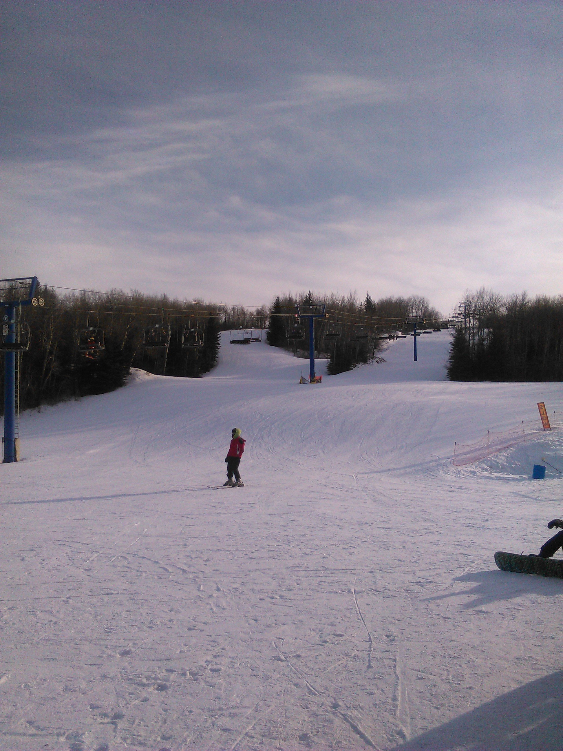 Winter sports scene at Table Mountain in Saskatchewan, Canada featuring a chalet, ski lift, and a skier enjoying the ski resort.