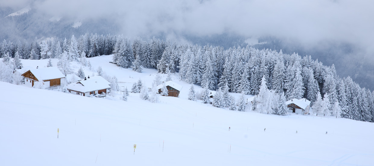 An enchanting winter scene at Eggberge in Uri Switzerland showcasing a bustling winter sports center amidst a stunning snowy landscape. A charming chalet is nestled nearby adding to the allure.