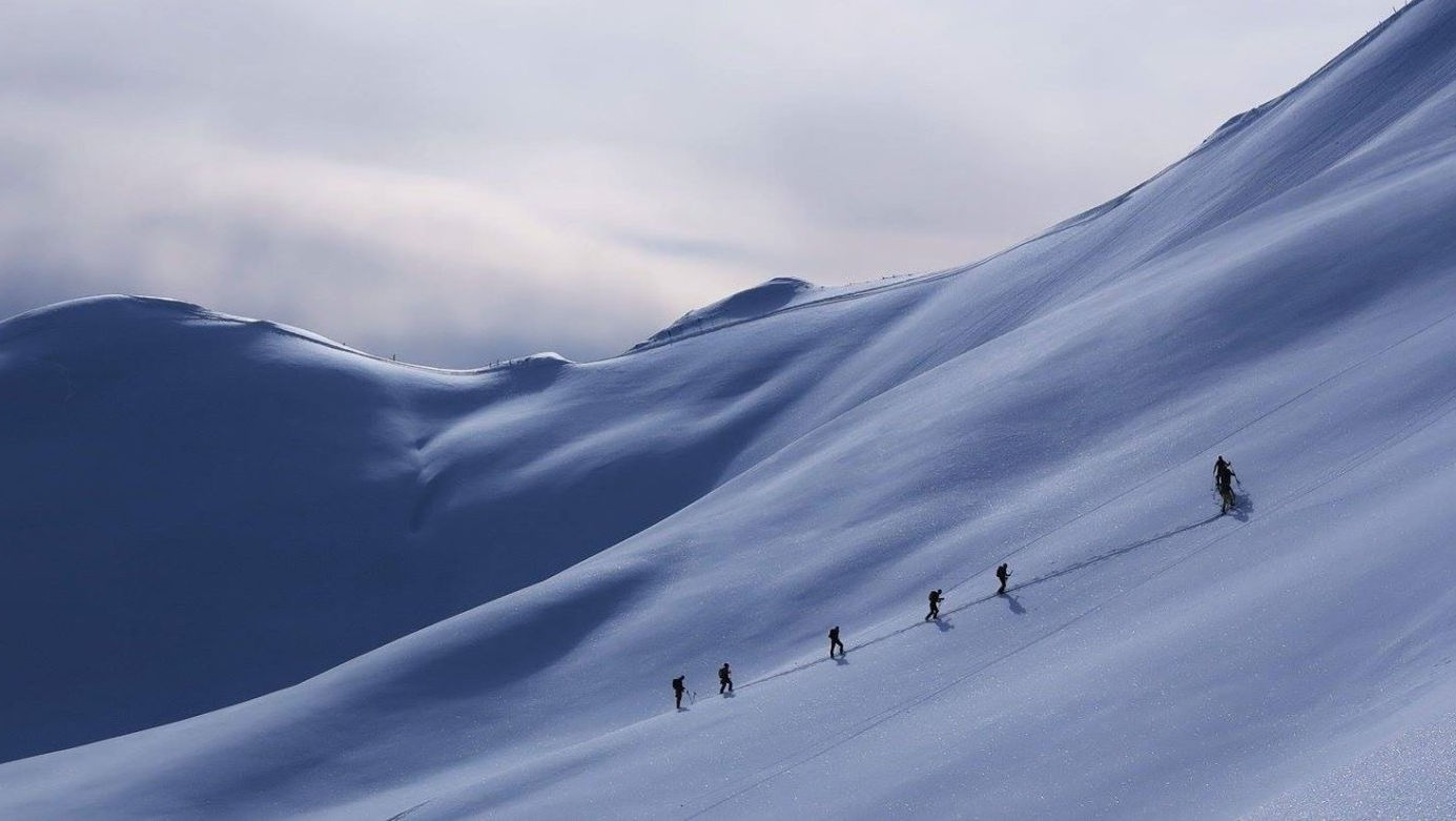 Eggberge in Switzerland - a group of people skiing down a snow covered mountain.