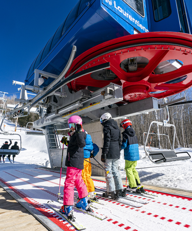 A ski lift operates at the vibrant Sommet Gabriel ski resort in Quebec Canada brimming with winter sports enthusiasts. A family enjoys skiing together creating lifetime memories.