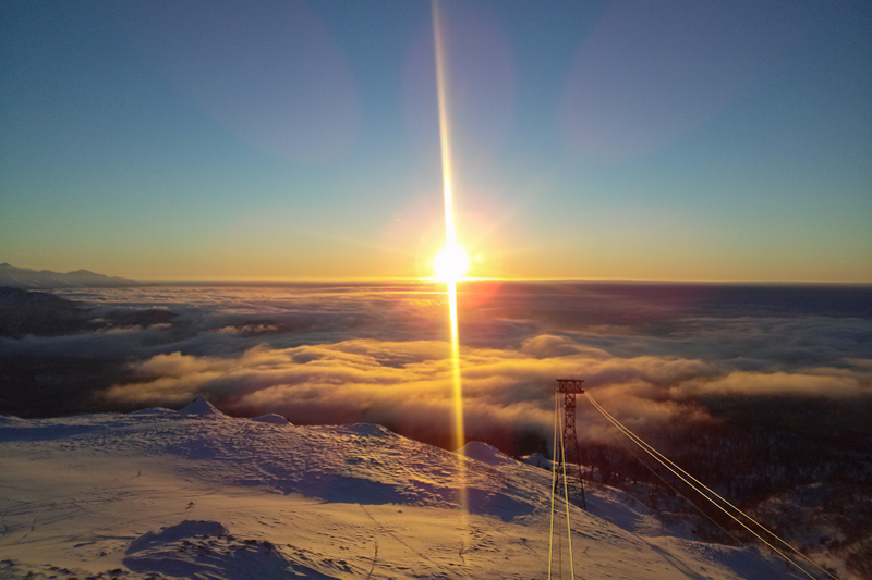 Asahidake in Japan - a mountain covered in snow with trees in the fore.