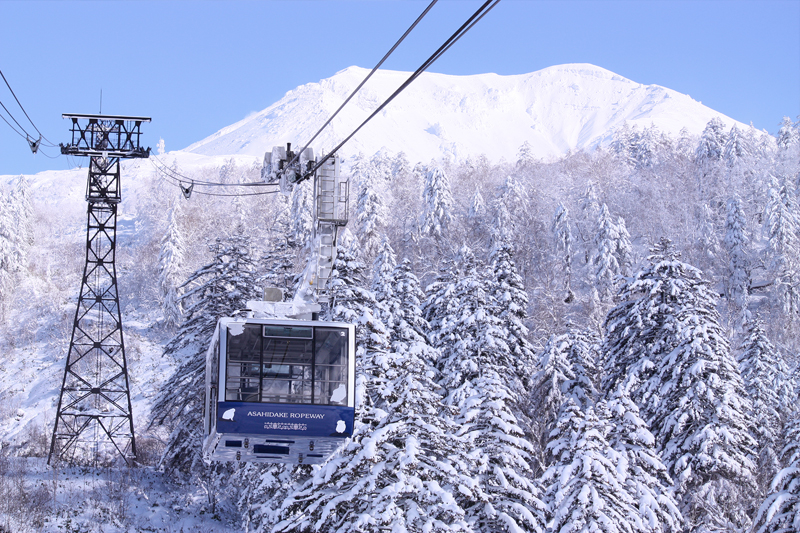 Asahidake in Japan - the sun is shining through the clouds over a snowy landscape.
