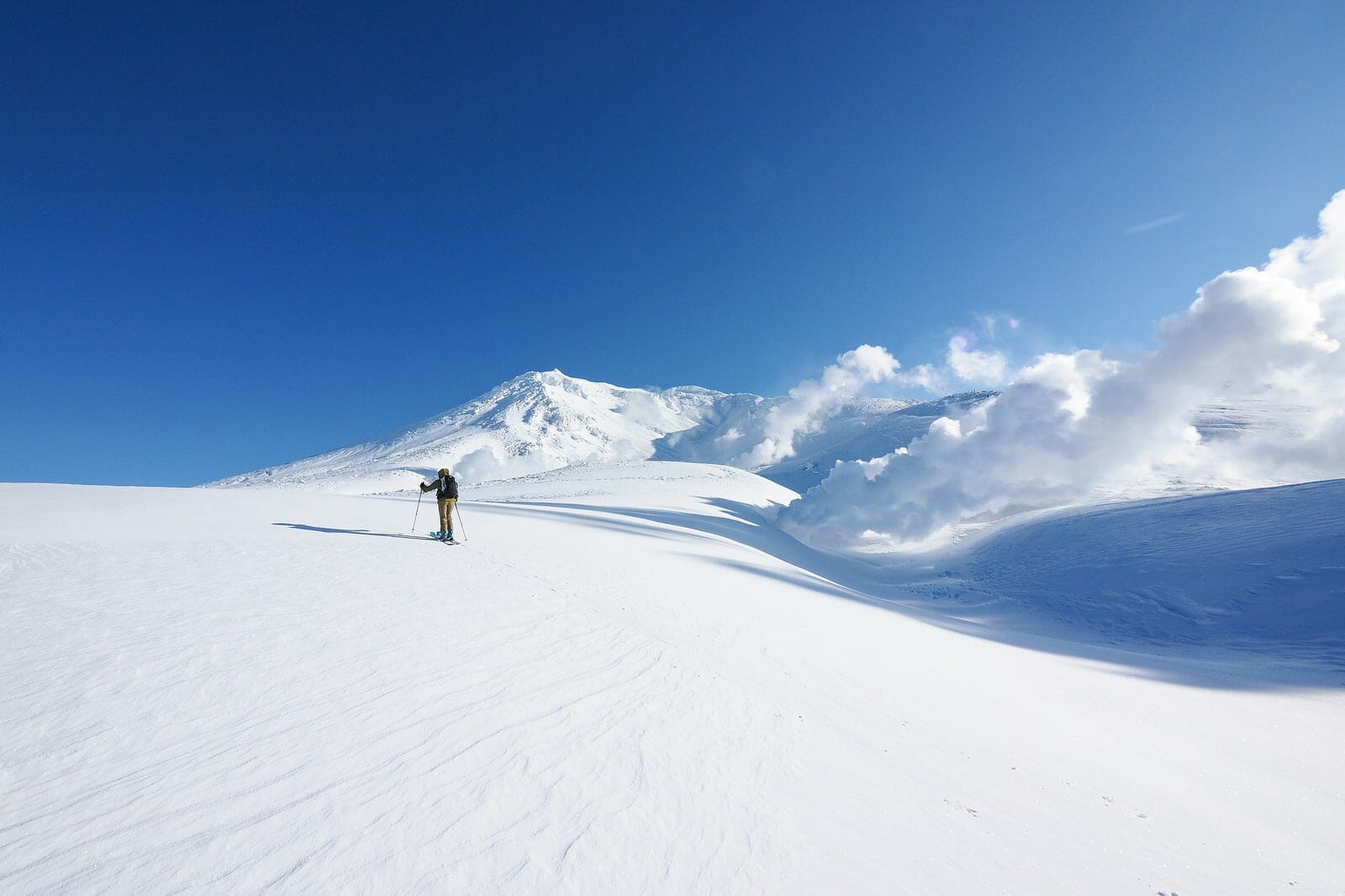 Asahidake in Japan - a person standing on top of a snow covered mountain.