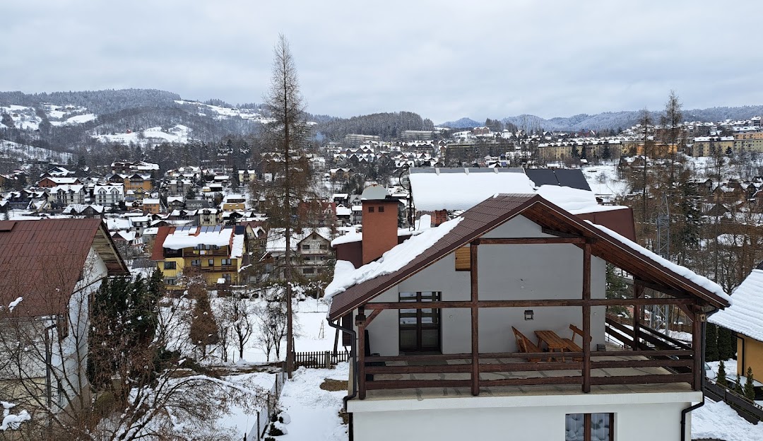 Winter scene in Palenica, Szczawnica, featuring the stunning snow-covered landscape of a ski resort, including a chalet and sports center facilities.