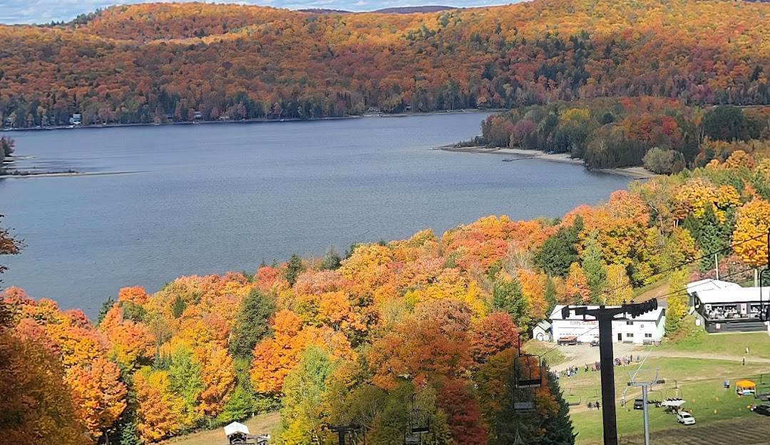 A scenic image of Sir Sam's ski resort in Eagle Lake Ontario showcasing a beautiful lake an inviting chalet the bustling ski resort and a lodge nestled amongst the mountain landscape.