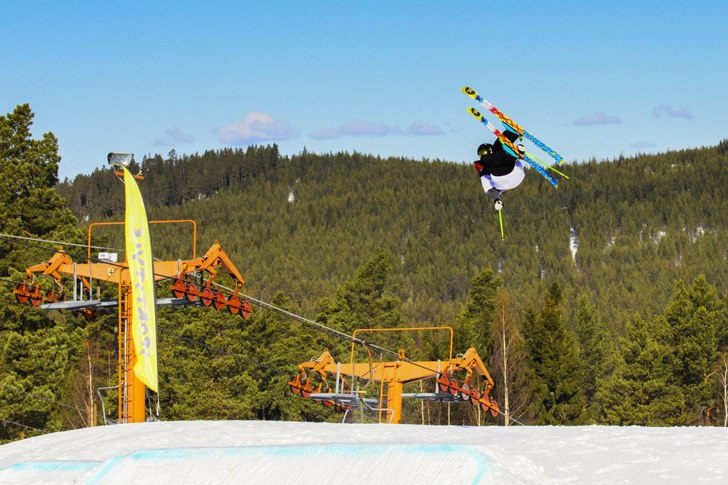 A skier and a snowboarder enjoying their winter sports at the bustling Gesundaberget ski resort in Sollerön Central Sweden. The scene includes a ski lift and a snow-filled landscape.