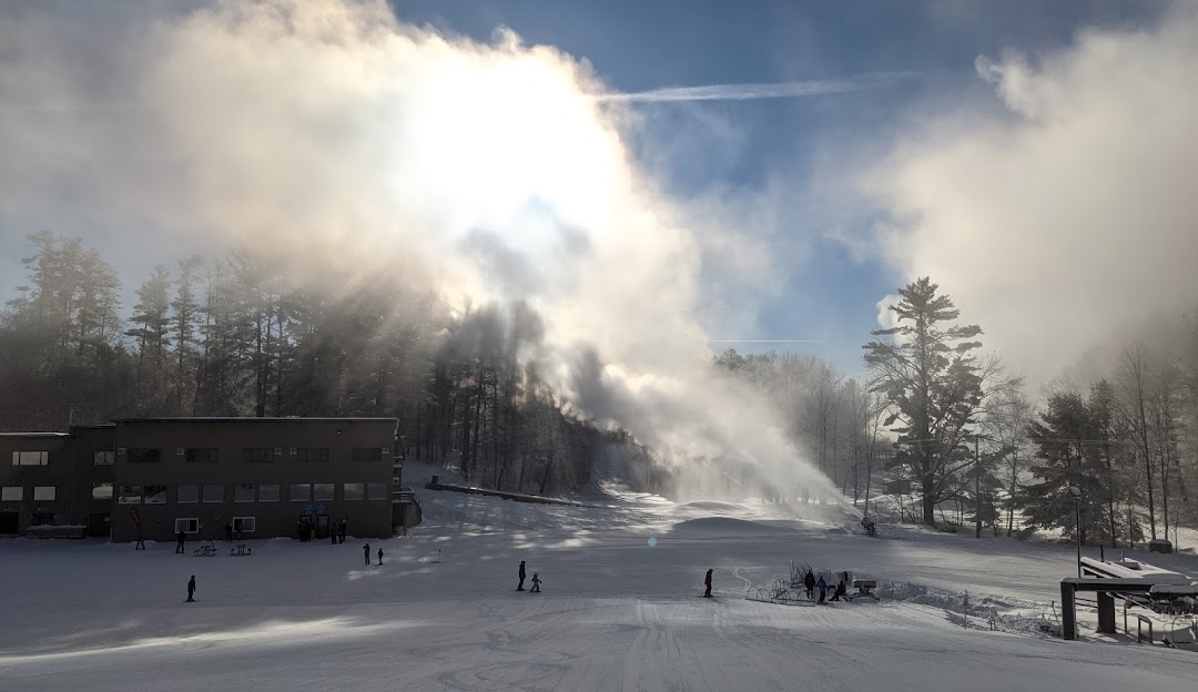 Winter sports enthusiasts enjoy skiing and snowboarding at King Pine ski resort in Madison, New Hampshire, amidst stunning winter scenery complete with a moving ski lift.