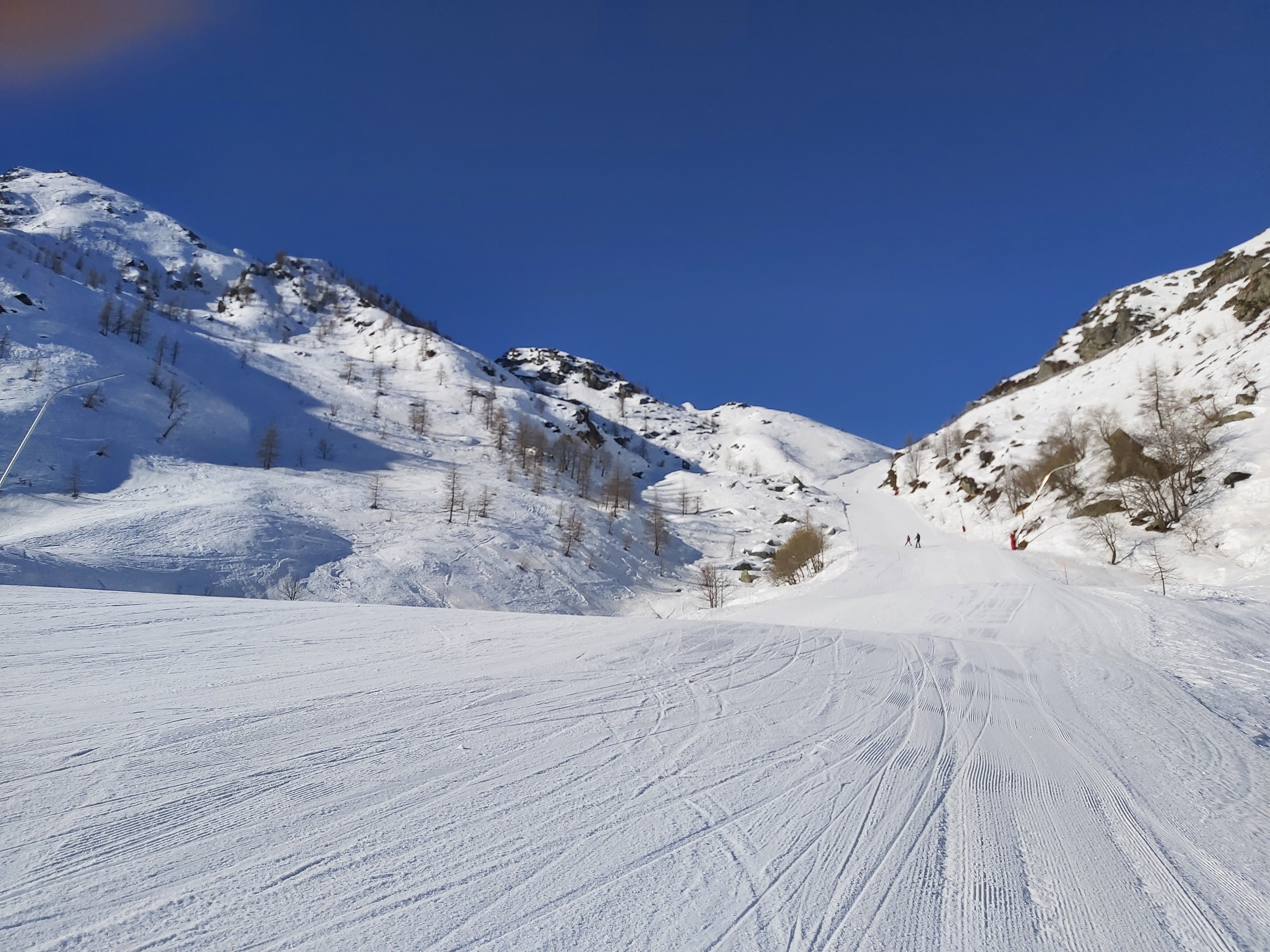 Winter scene at Pian Benot Sciovie Usseglio in Turin, Italy, featuring a skier descending snow-covered slopes at a ski resort with a quaint challet nearby.