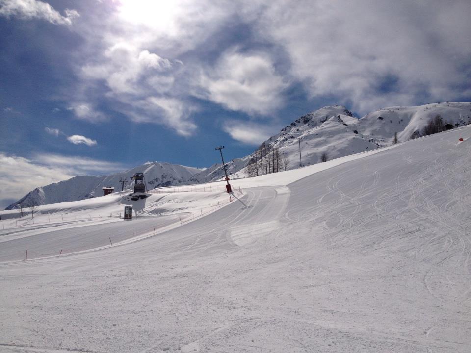 A charming chalet nestled in Pian Benot Sciovie Usseglio, Turin, Italy. Ski enthusiasts enjoy the ski resort, swooping down the snow-covered slopes on a beautiful winter day.