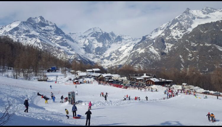 A picturesque winter scene at Pian Benot Sciovie Usseglio ski resort in Turin, Italy featuring a charming chalet amidst the snow-covered slopes bustling with sports activities.