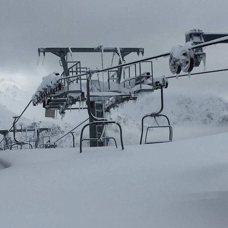 Scenic view of Pian Benot Sciovie Usseglio, a ski resort in Turin, Italy. A ski lift cuts through snow-covered slopes with a picturesque challet nestled amidst the winter sports scene.