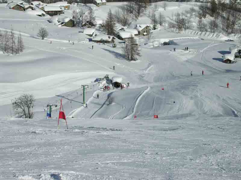 Winter sports scene at Pian Benot Sciovie Usseglio in Turin Italy featuring a cozy challet a bustling ski resort and skiers enjoying the slopes.