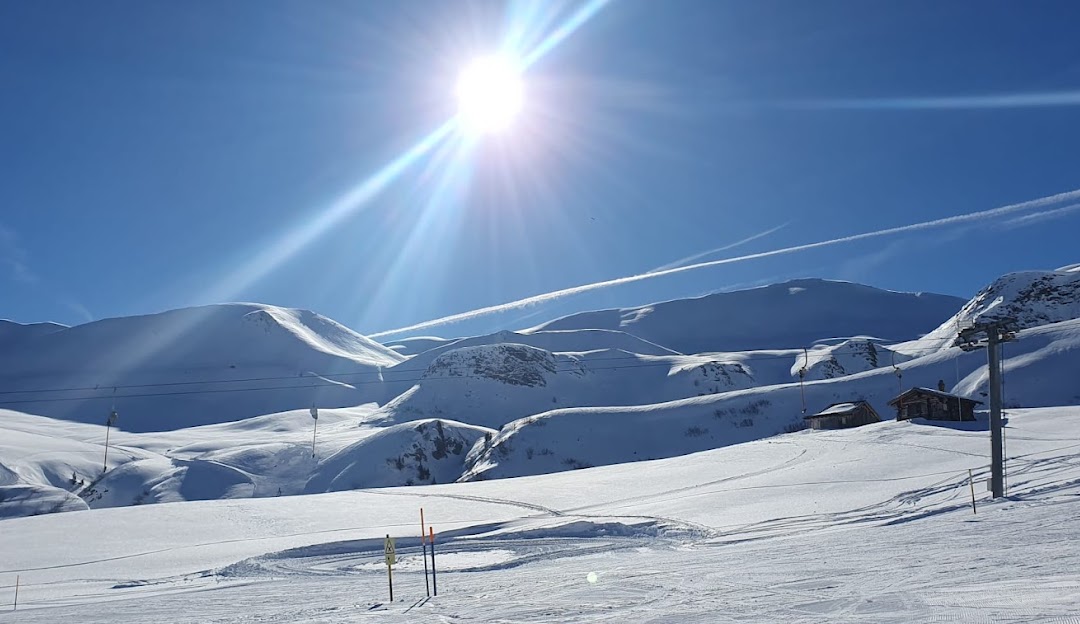 Winter sports scene at Fideriser Heuberge in Eastern Switzerland, featuring skiers enjoying the slopes near a charming chalet and the encompassing ski resort.
