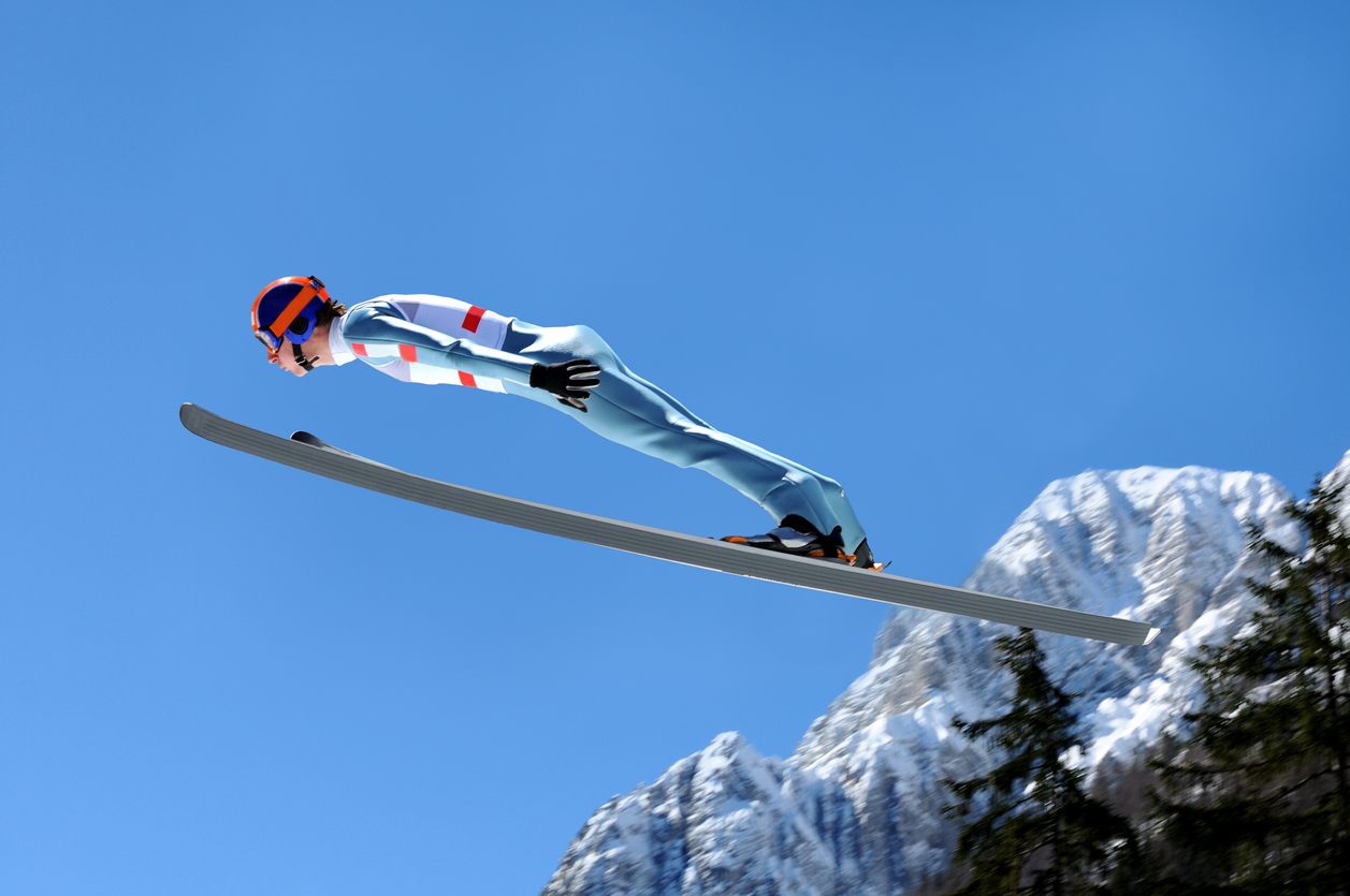 A skier descending a pristine, snow-covered slope at Fideriser Heuberge in Eastern Switzerland, with a ski lift and snowboarding facilities in the backdrop.