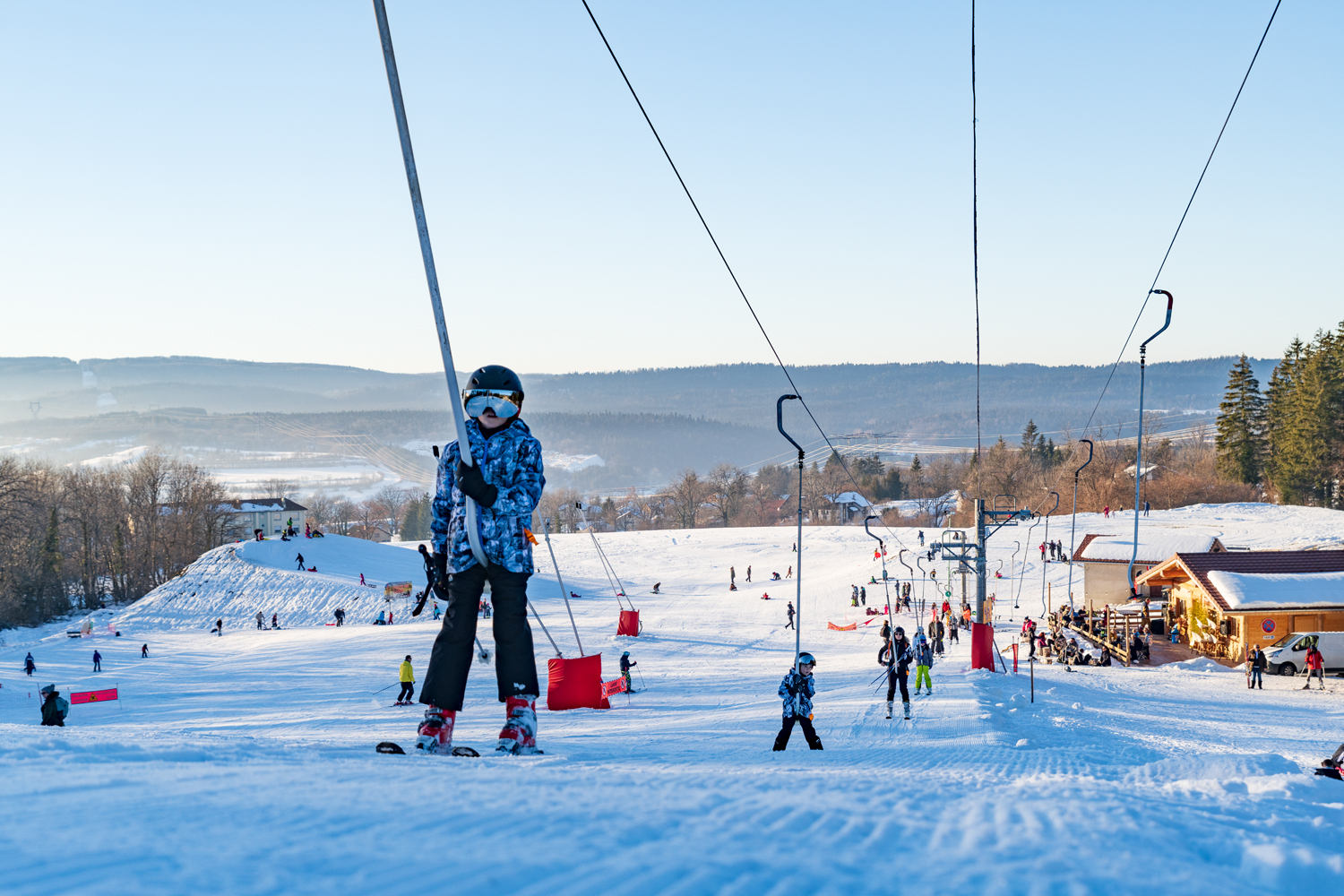 Image of a bustling winter sports scene at Terre-Ronde ski resort in France featuring a skier and a ski lift amidst a snowy landscape.