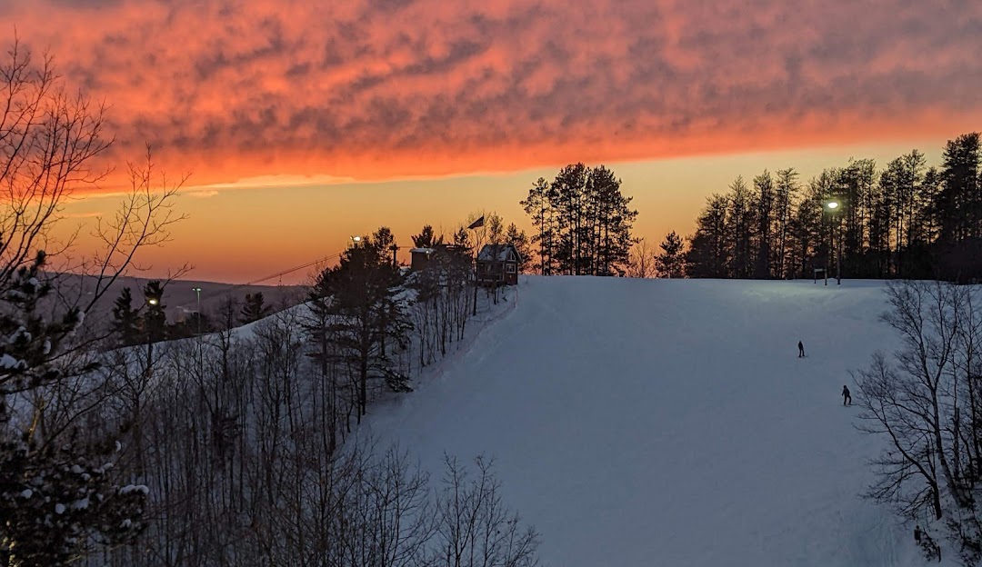 Winter sports enthusiasts enjoy a sunny day at Mont Ripley ski resort in Hancock, Michigan, amidst stunning snow-laden scenery.