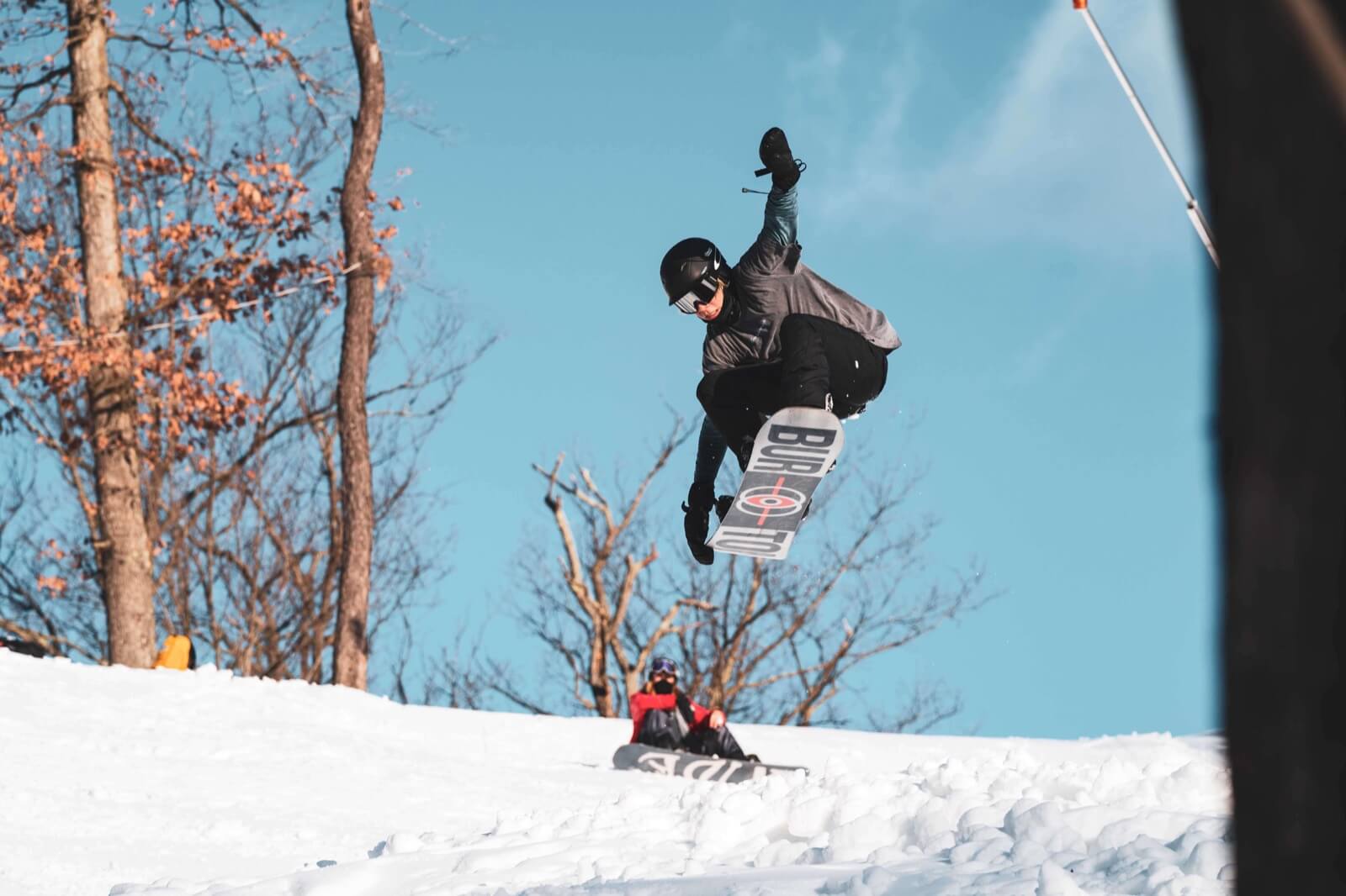 A snowboarder captured in action at Bryce Resort in Virginia, USA. They are skillfully maneuvering their way down the snow-covered slope, leaving a trail of fresh powder behind them.