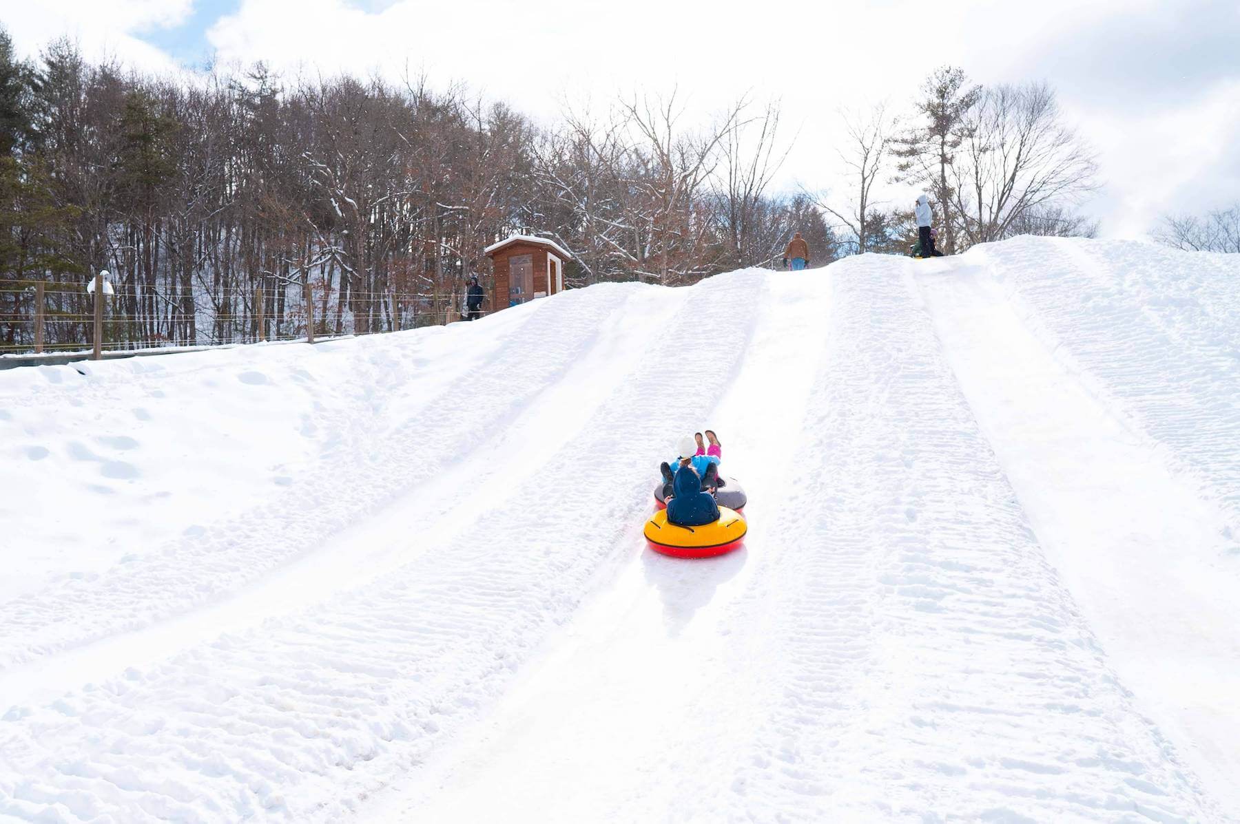 Winter scene at Bryce Resort, Virginia, prominently featuring a snowmobile amidst a winter sports scene, with a chalet and ski resort faintly visible in the background.